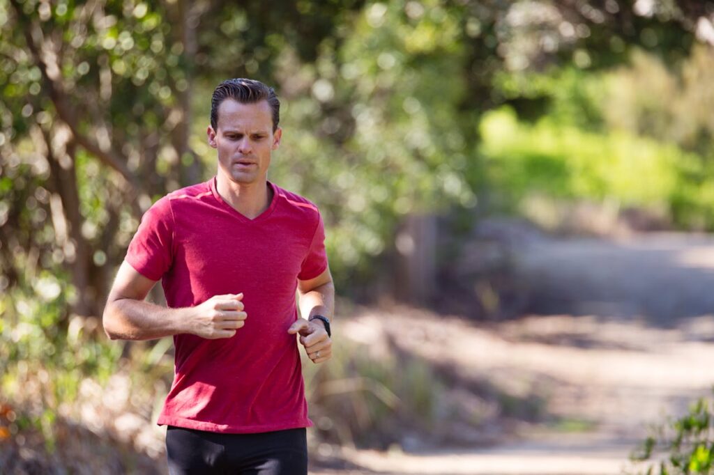 Man Running on Path Surrounded With Trees
